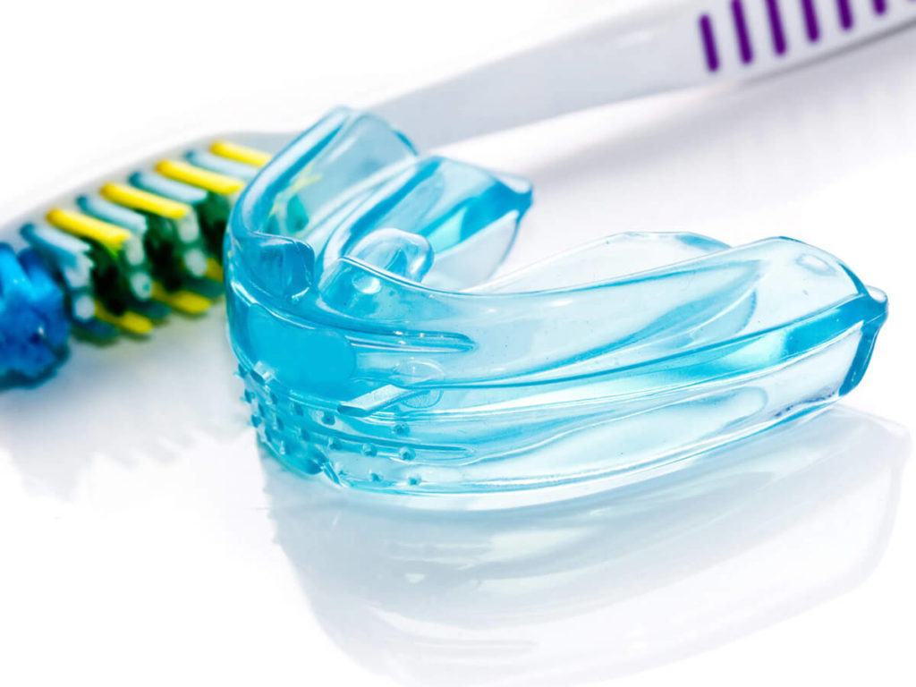 Toothbrush and mouthguard on white reflective backdrop