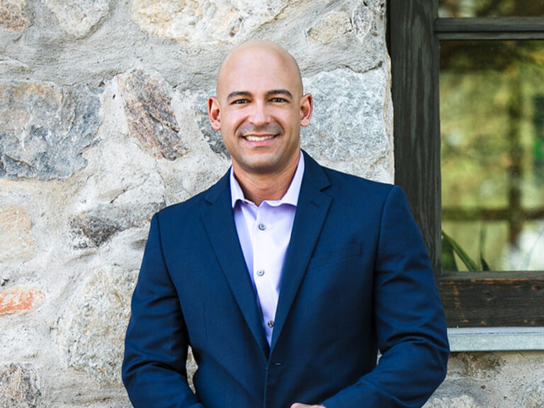 Close up of Dr. Tobon standing in front of stone building