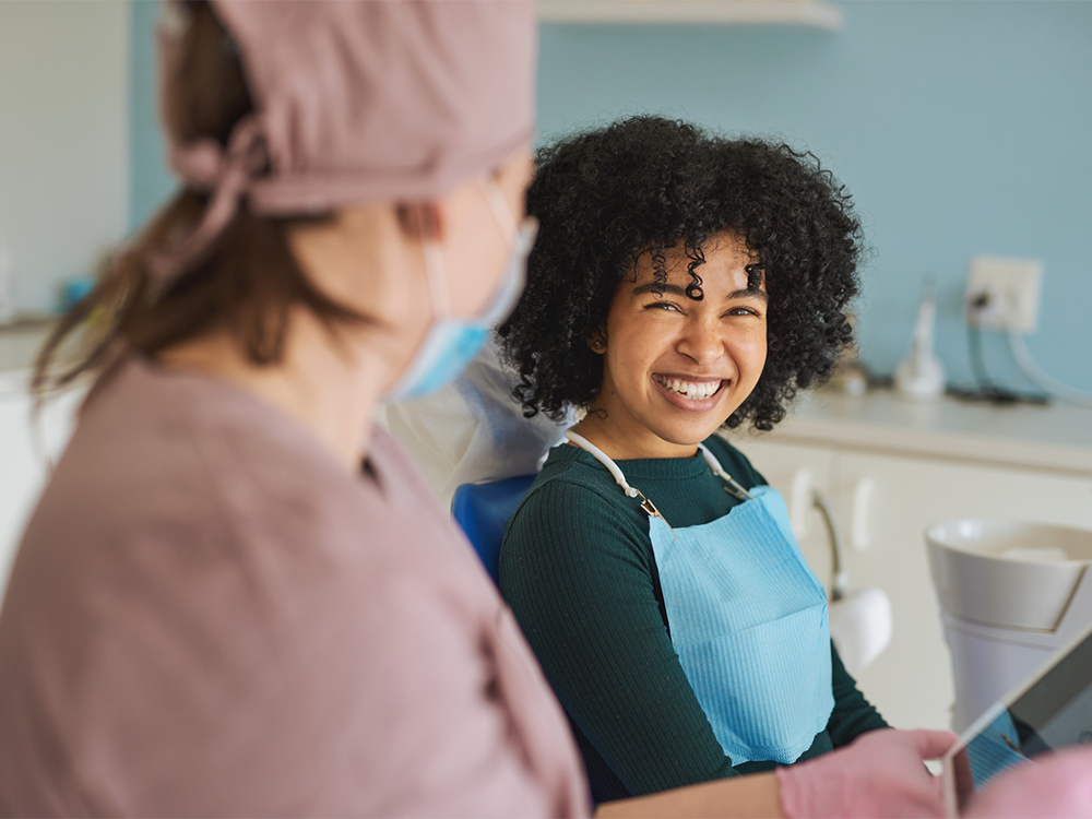patient smiling while talking with dental assistant after exam