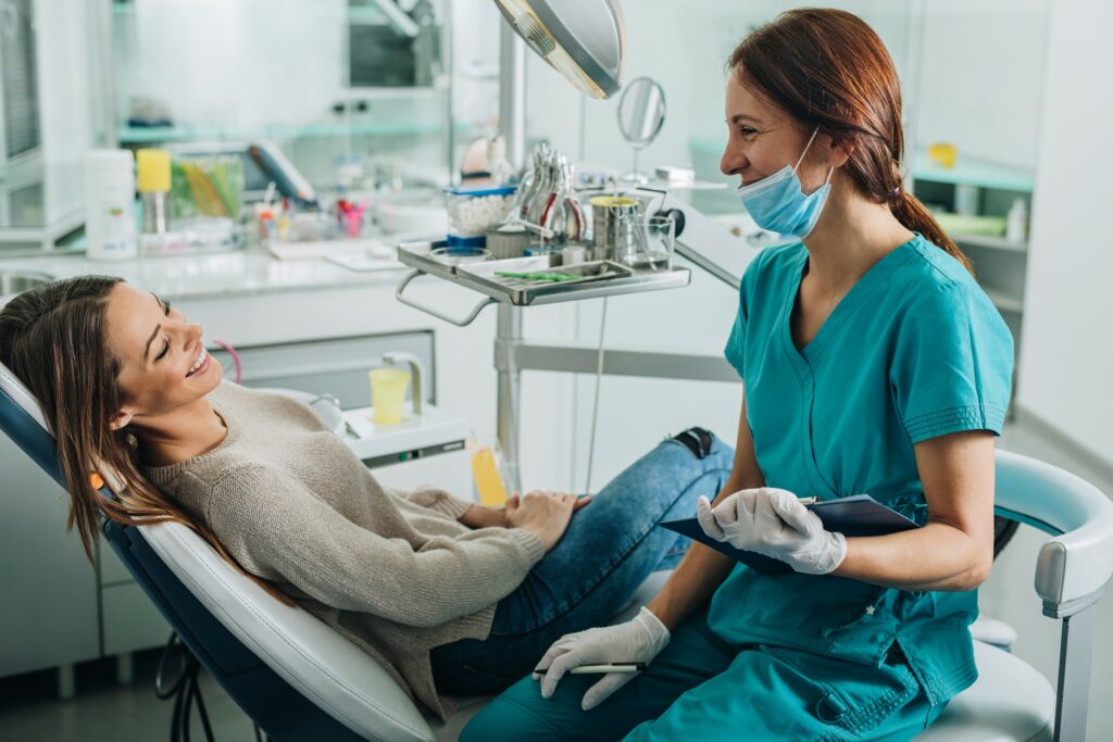 Patient sitting in exam room talking with dental assistant