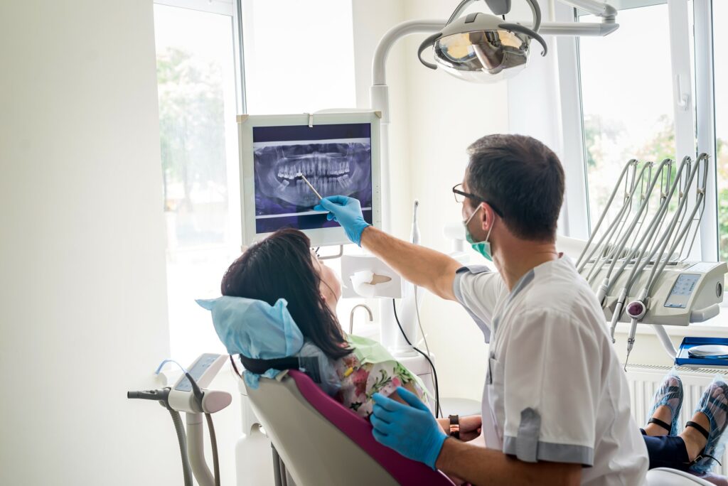 Dentist pointing to dental x-ray during exam